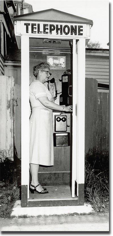 Kath Gray making the last call in the booth on Water Street, Castine, before the operator-assisted crank telephone system was upgraded to a dial system in 1956. Photograph by Ed Langlois, CHS Collections